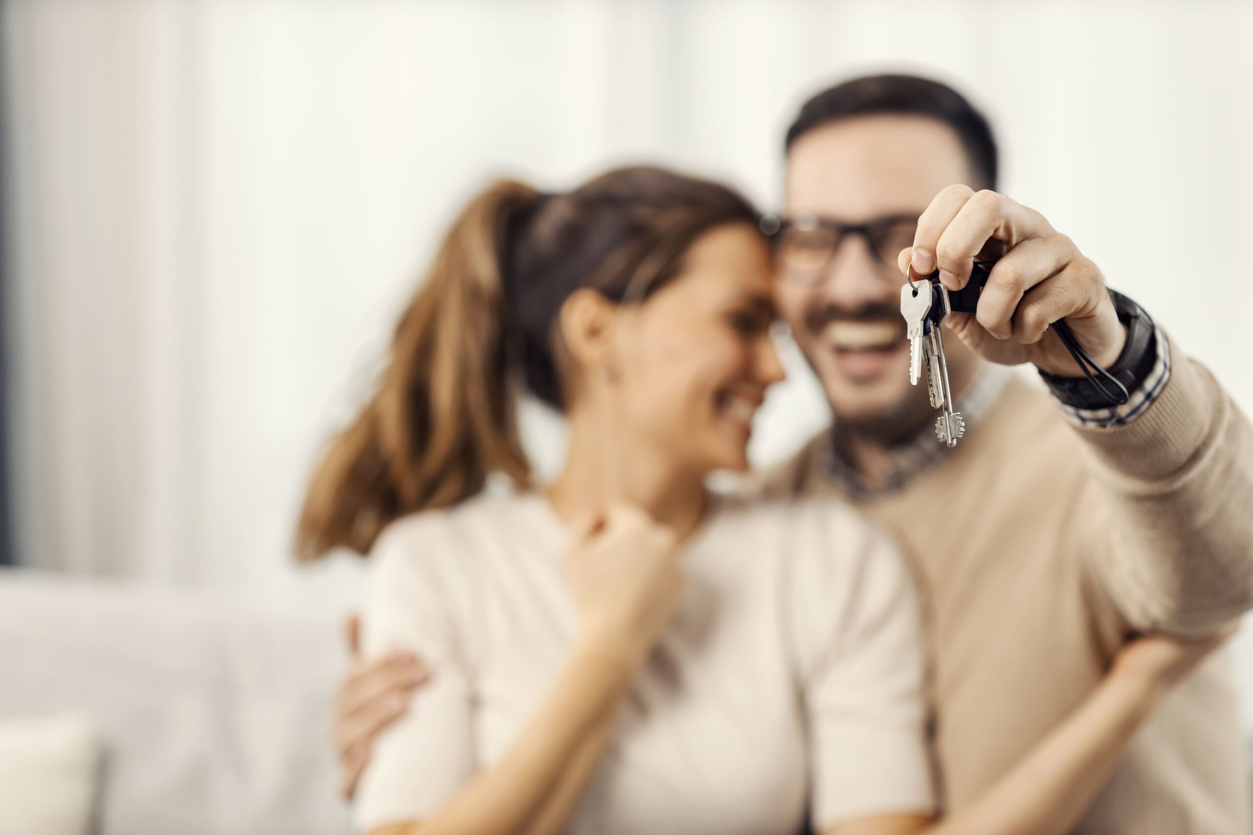 Família feliz em frente à nova casa própria com chave nas mãos